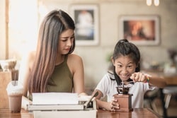 Woman and child using a manual coffee grinder